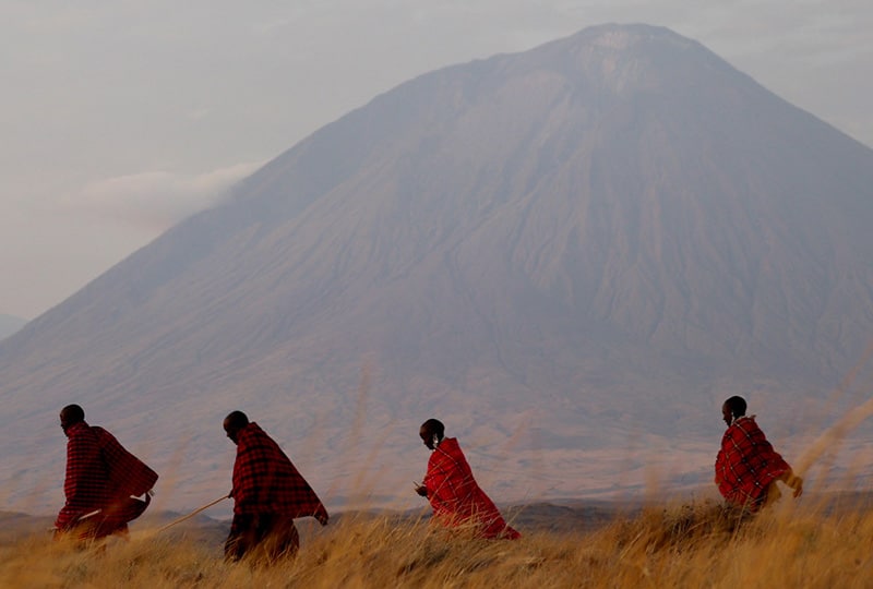 Four Indigenous People walking with a mountain in the backdrop.