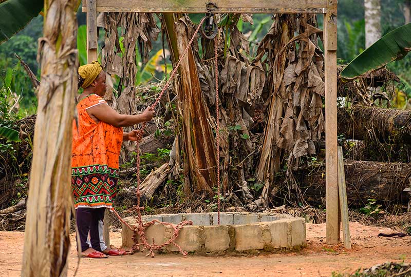 a woman collecting water from well.