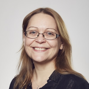 Sophie Grange-Chamfray smiling at the camera wearing a black shirt and glasses