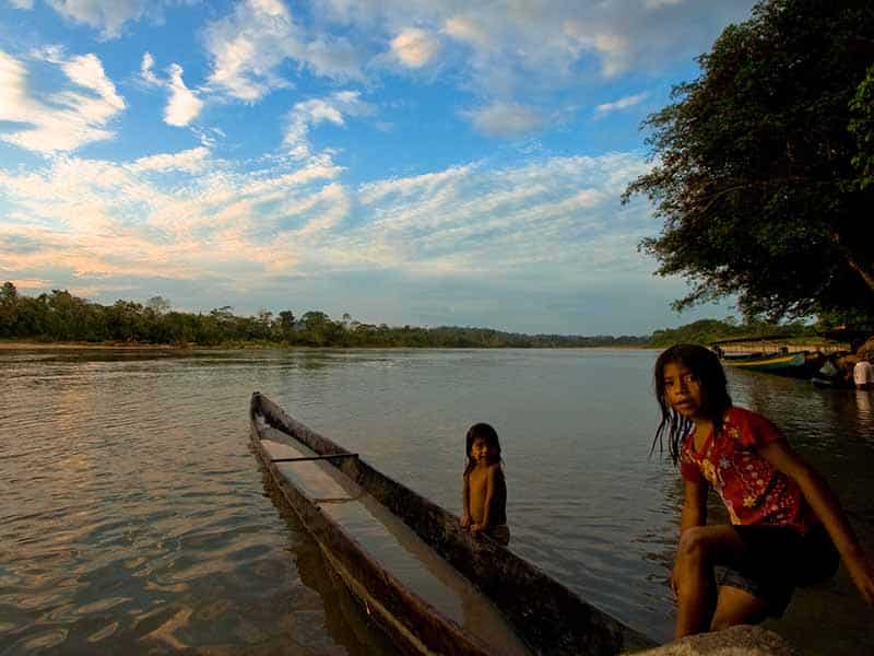 Girls play around a canoe in the Napo river