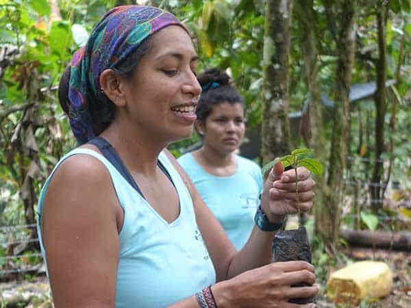 a smiling person holding a small potted plant in their hand