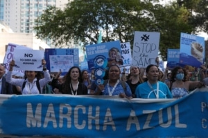 A protest with placards saying 'stop deep sea mining' and a blue banner held at the front of the crowd reading 'Marcha azul'