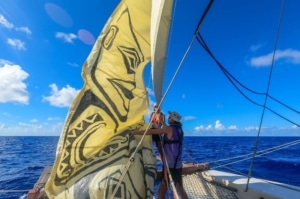 A sailboat at sea with art on the sail