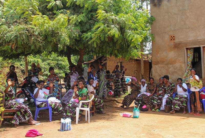 a group of women sat outside, some are smiling and waving.