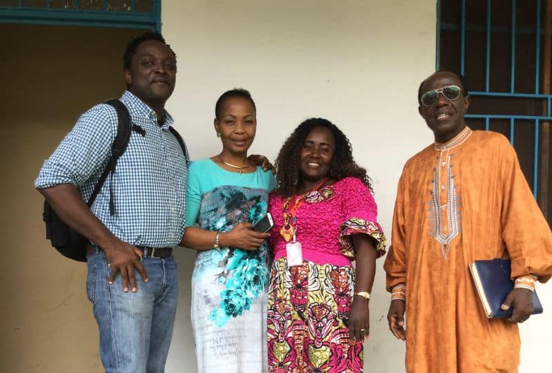 Two men and two women smiling outside a house