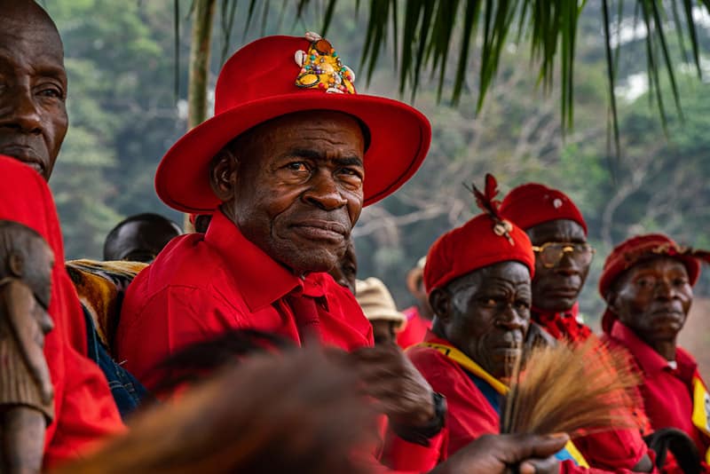 A man wearing a bright red shirt and hat in a formal gathering