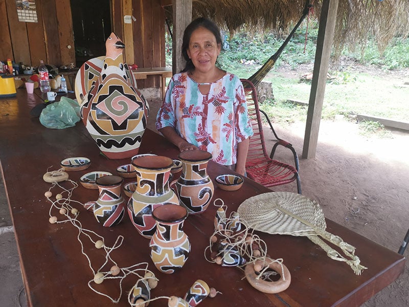 A woman displaying pottery made with clay of different colours.