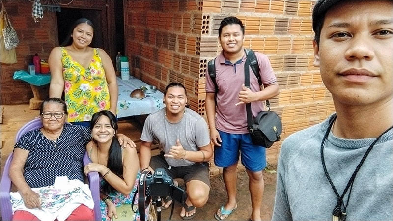 Group selfie with young Indigenous youth with camera equipment with an older member of the Terena community.