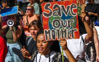 a woman holding a sign saying 'save our mother'