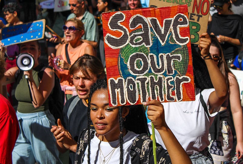 a woman holding a sign saying 'save our mother'