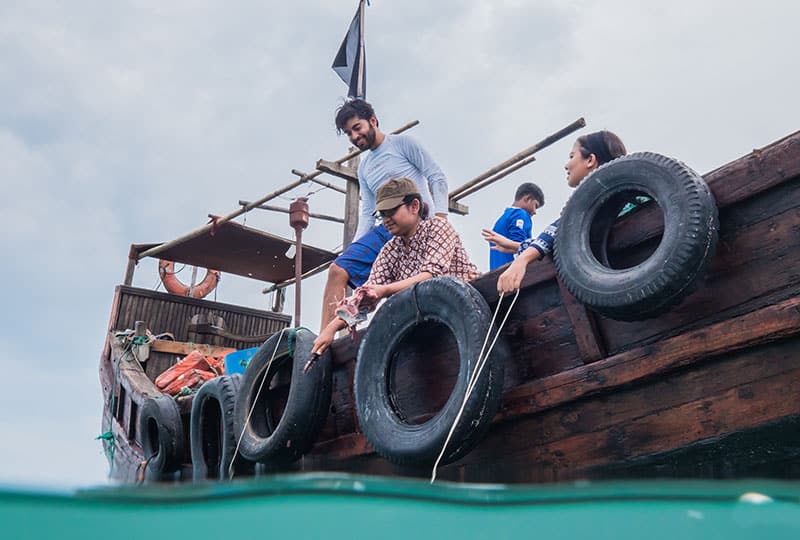 Scientist Alifa Haque completes a task off the side of a fishing boat with colleagues/fishers.