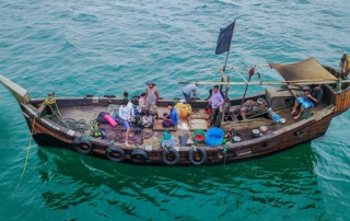 A wooden fishing boat with fishermen on a turquoise sea
