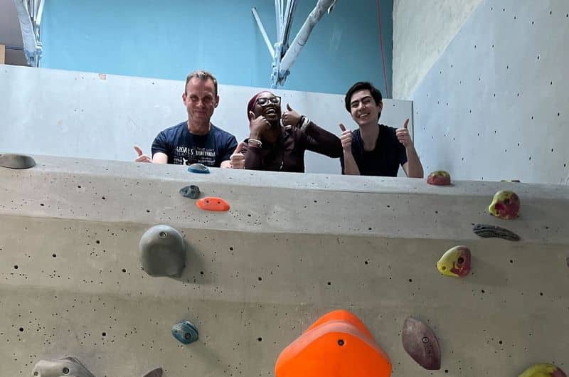 Three members of Synchronicity Earth's communications team pose for a photo at the climbing gym.