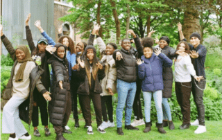 Group of smiling young people with their hands held in the air