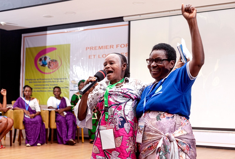 Marie Dorothée Lisenga Bafalikike (left), an Indigenous Baaka woman from Yahuma territory in the DRC chants in solidarity with another forum participant, who has a triumphant fist raised in the air