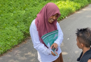 A woman in a hijab shows a student an educational poster