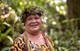 Cook Islands Indigenous woman smiles wearing a headdress of leaves.
