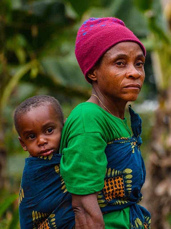 A Baka woman in the forest near the village of Assoumindele, in Cameroon, carries a child on her back
