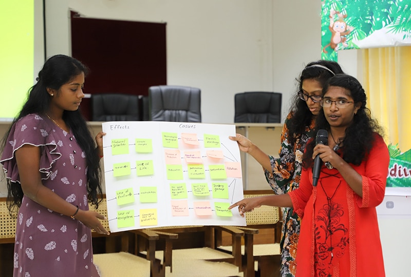 Three women presenting at a conference with a flip chart