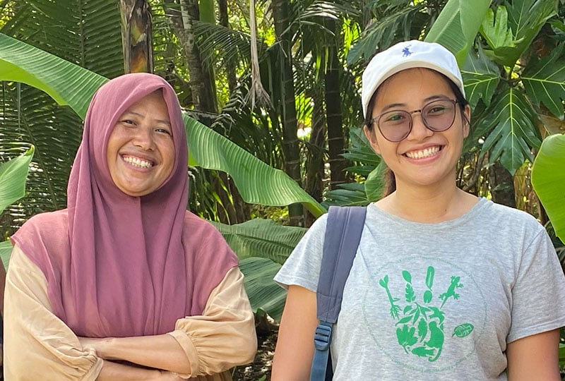Asnim Alyoihana Lanusi (left) and Sheherazade (right) smile in front of a leafy background. 