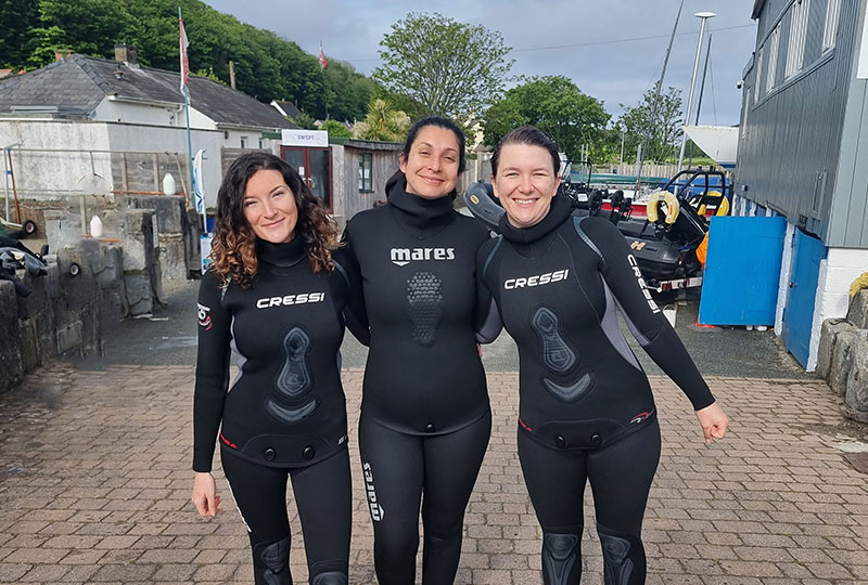 Geanie, Sabrina and Anna from the Synchronicity Earth team in wetsuits.