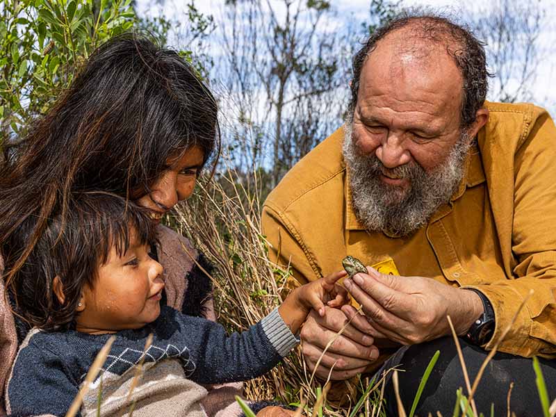 Two adults and a child closely observing a bug