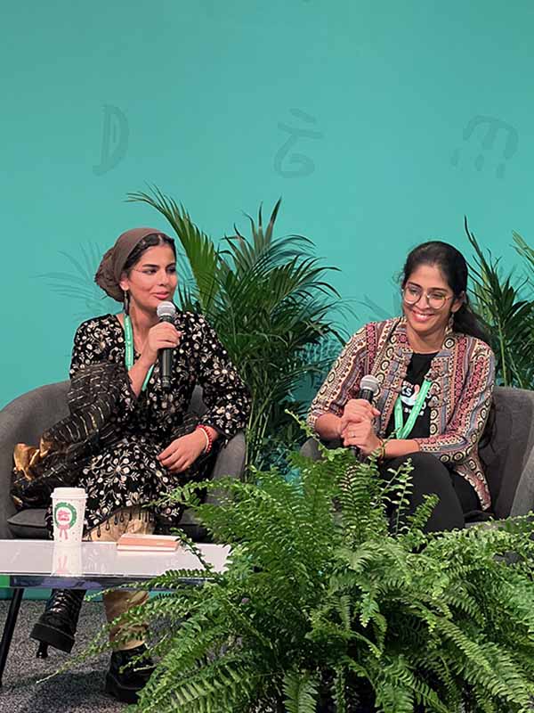 Two young women holding microphones sitting together in conversation at CBP COP15 in Montreal
