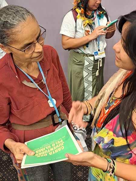 Taily Terena of the Indigenous Terena Youth movement presents a letter to another delegate at COP27