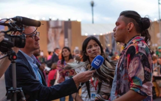 One journalist with camera and microphone interviews two members of Indigenous Terena Youth delegation at COP27 climate conference