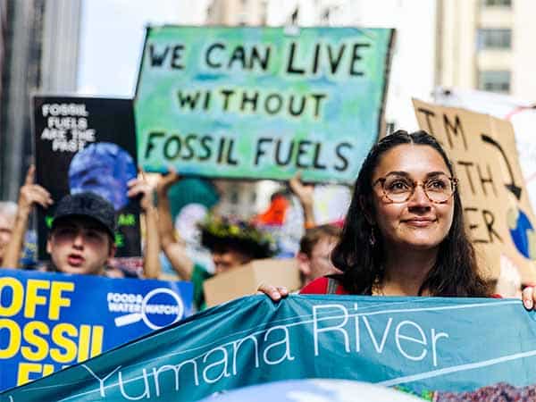 Protesters holding a sign that says "We can live without fossil fuels"