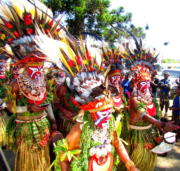 People dancing in a parade wearing multi-coloured cultural dress