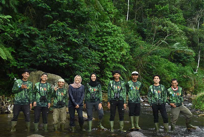 people standing for a photo in the rainforest.