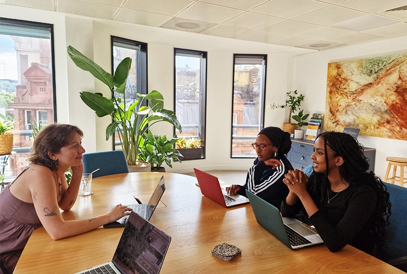 Three people have a meeting in a boardroom