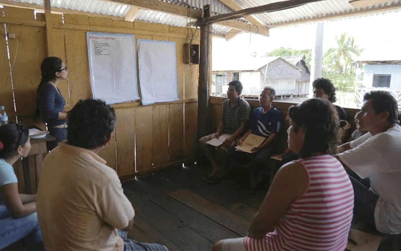 Community members sit looking at posters on the wall during a workshop on agrobiodiversity Sapuena, Peru