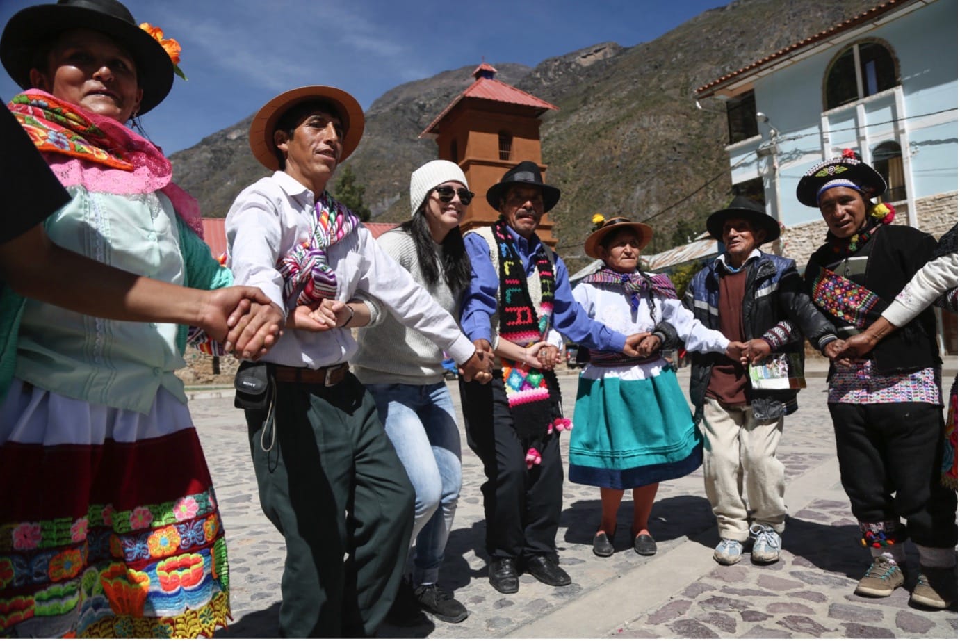 People in an Indigenous village stand together with linked hands against an Andean mountain backdrop in celebration at the first annual meeting of the association of native potato guardians of central Peru
