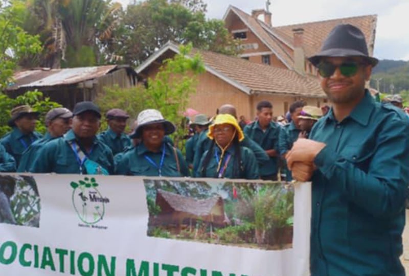 A man smiling and holding a sign.