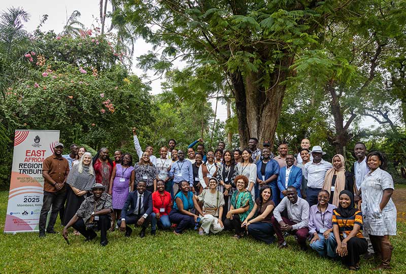 A group of people posing for a photo with a sign on the side that says 'East Africa Regional Tribunal'