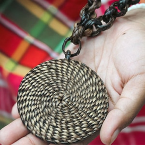 A hand holds out a piece of woven Indigenous art. © Ugnayin PH