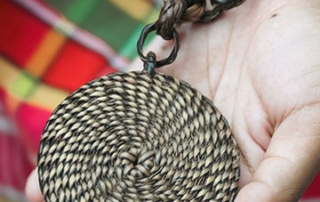 A hand holds out a piece of woven Indigenous art. © Ugnayin PH