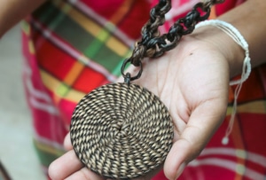 A hand holds out a piece of woven Indigenous art. © Ugnayin PH